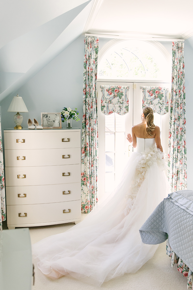 Bride in her childhood home before the wedding ceremony looking out the window